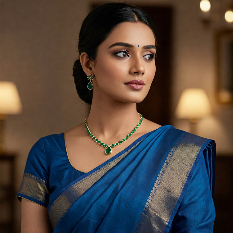 Elegant Indian model in traditional attire showcasing a modern Feelori emerald necklace and earrings set. Sources and related content