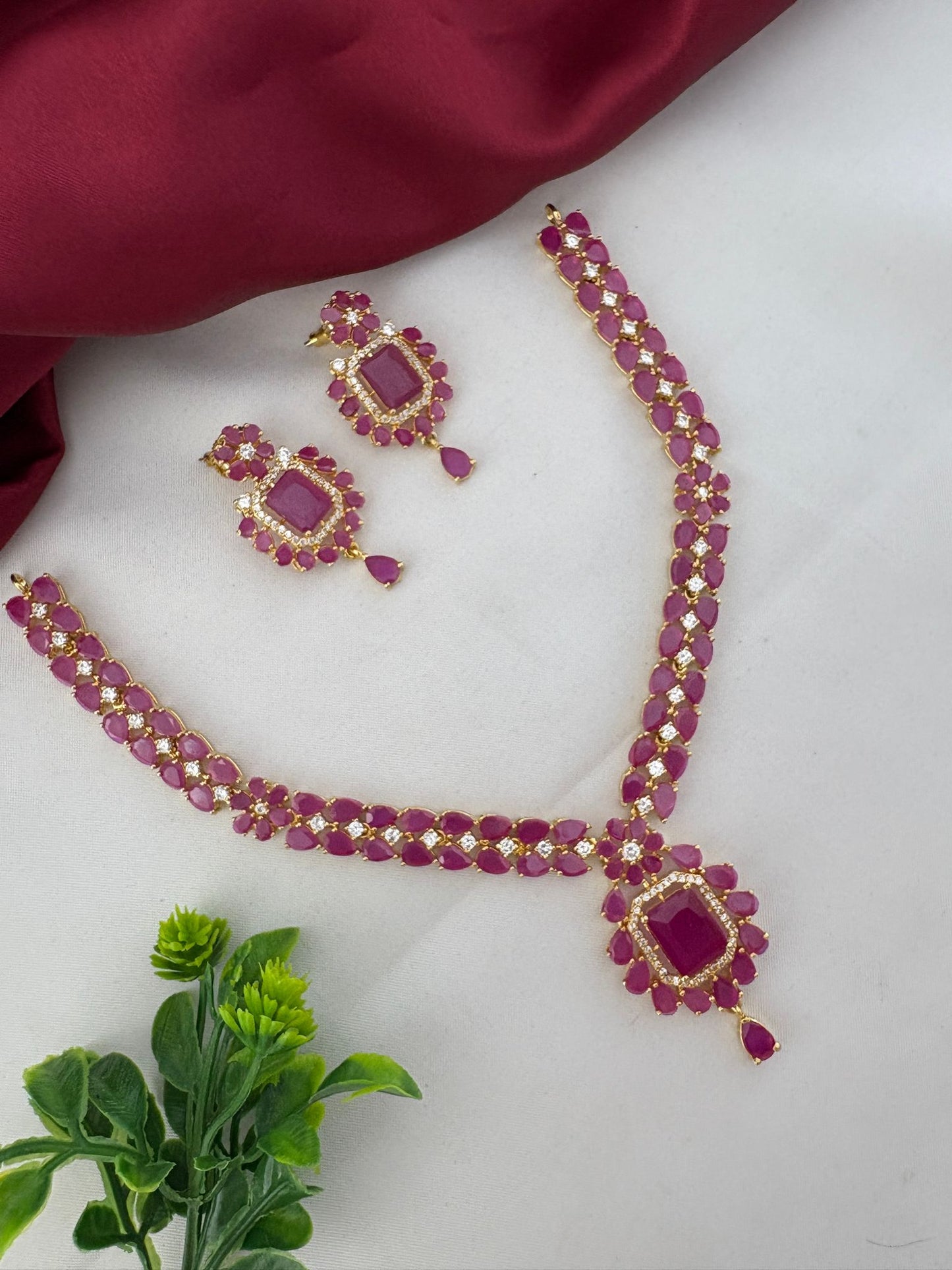 FeelOri Cascade Ruby & AD Vine Necklace Set styled with plant and fabric. Chennai Elegance collection by feelori.