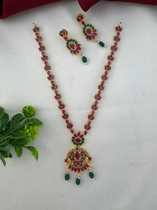 Clear product shot of the FeelOri Chettinad Bloom Ruby & Emerald Choker with accompanying earrings, showcasing stone details.