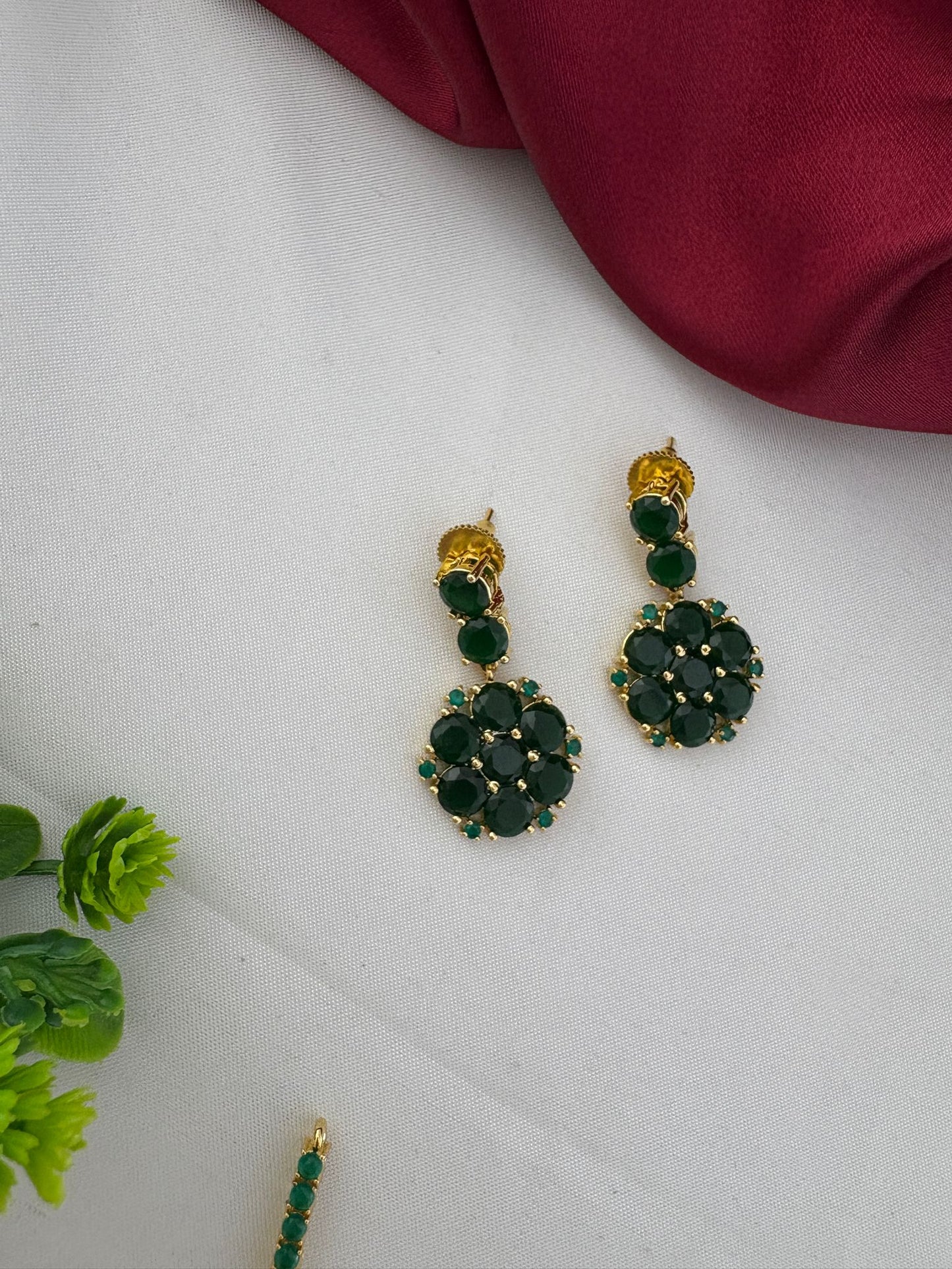 Detailed close-up of the FeelOri Deccan Spring Emerald earrings, showing the floral design and vibrant green stones, part of the necklace set.