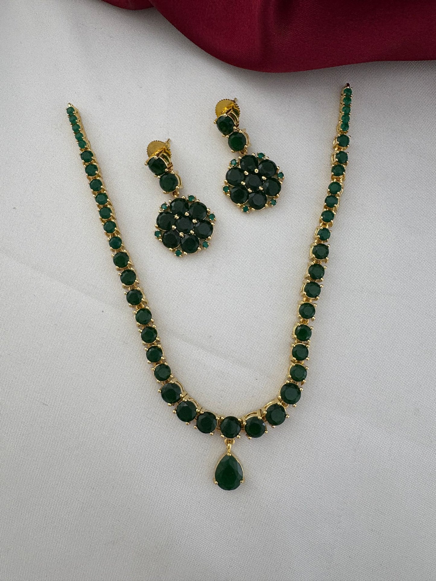 Clear top-down view of the FeelOri Deccan Spring Emerald Short Necklace Set, highlighting the gold finish and green stone arrangement.