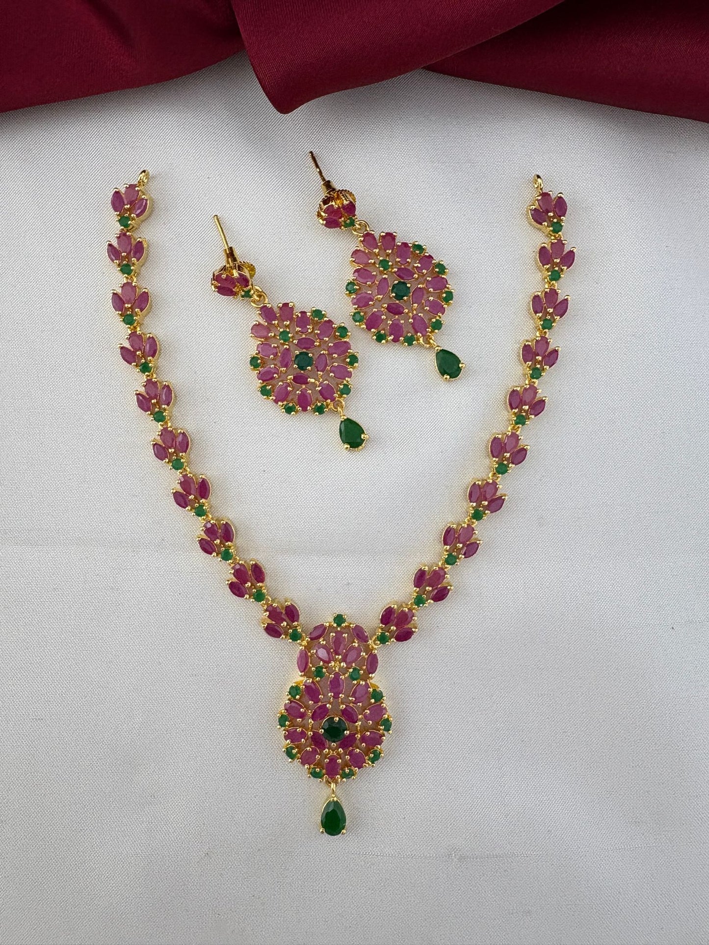 FeelOri Kerala Temple Duo Ruby & Emerald Necklace Set - Styled on fabric.