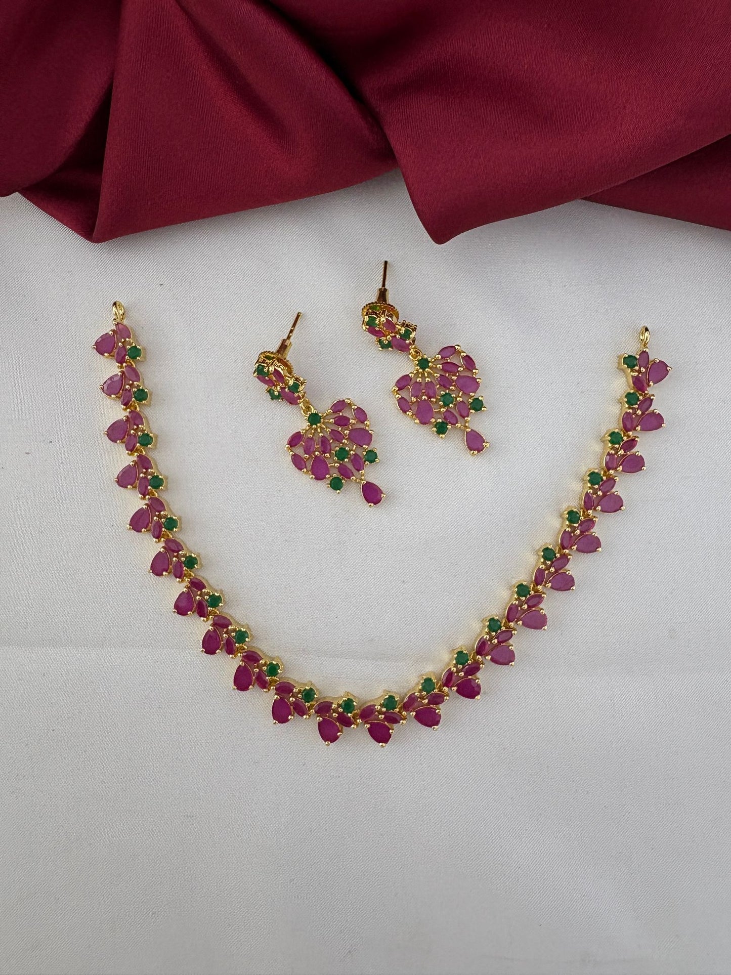 FeelOri Mysore Vasantham Ruby & Emerald Short Necklace Set with matching earrings, full view on a white and maroon background.