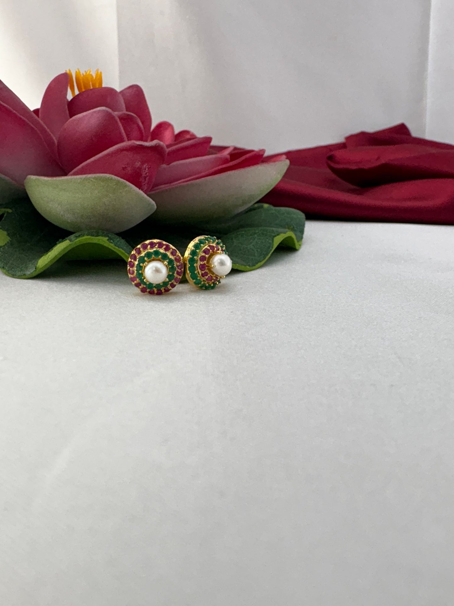 FeelOri pastel multi-color AD stud earrings elegantly arranged with decorative lotus on dreamy fabric backdrop
