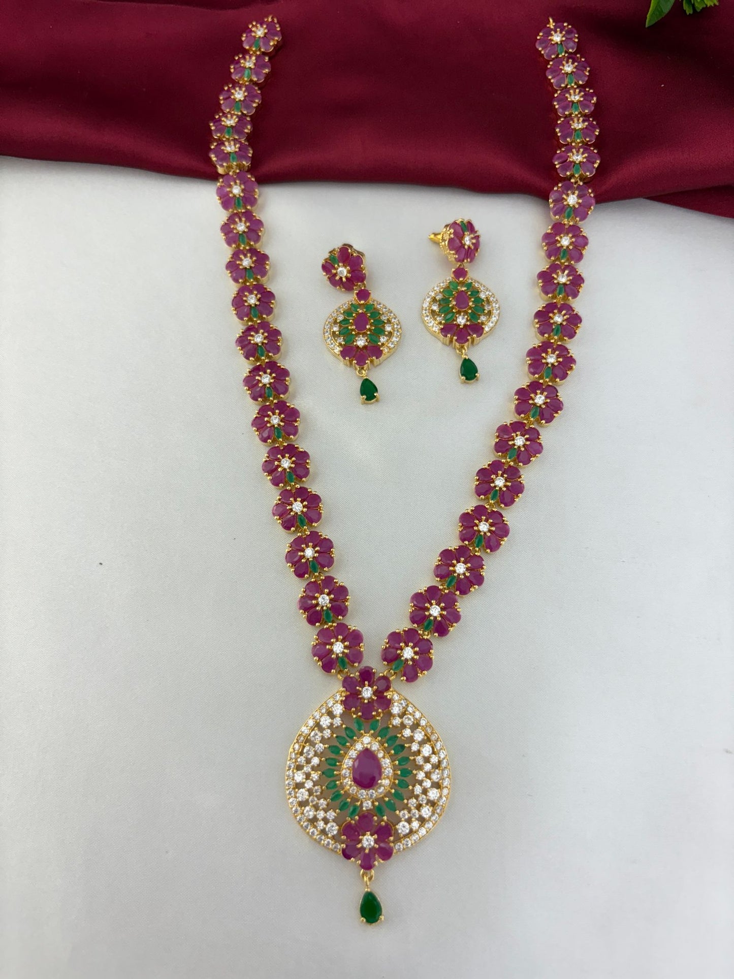 Feelori complete traditional gold-plated AD necklace set with ruby and emerald stones, including matching earrings, displayed.