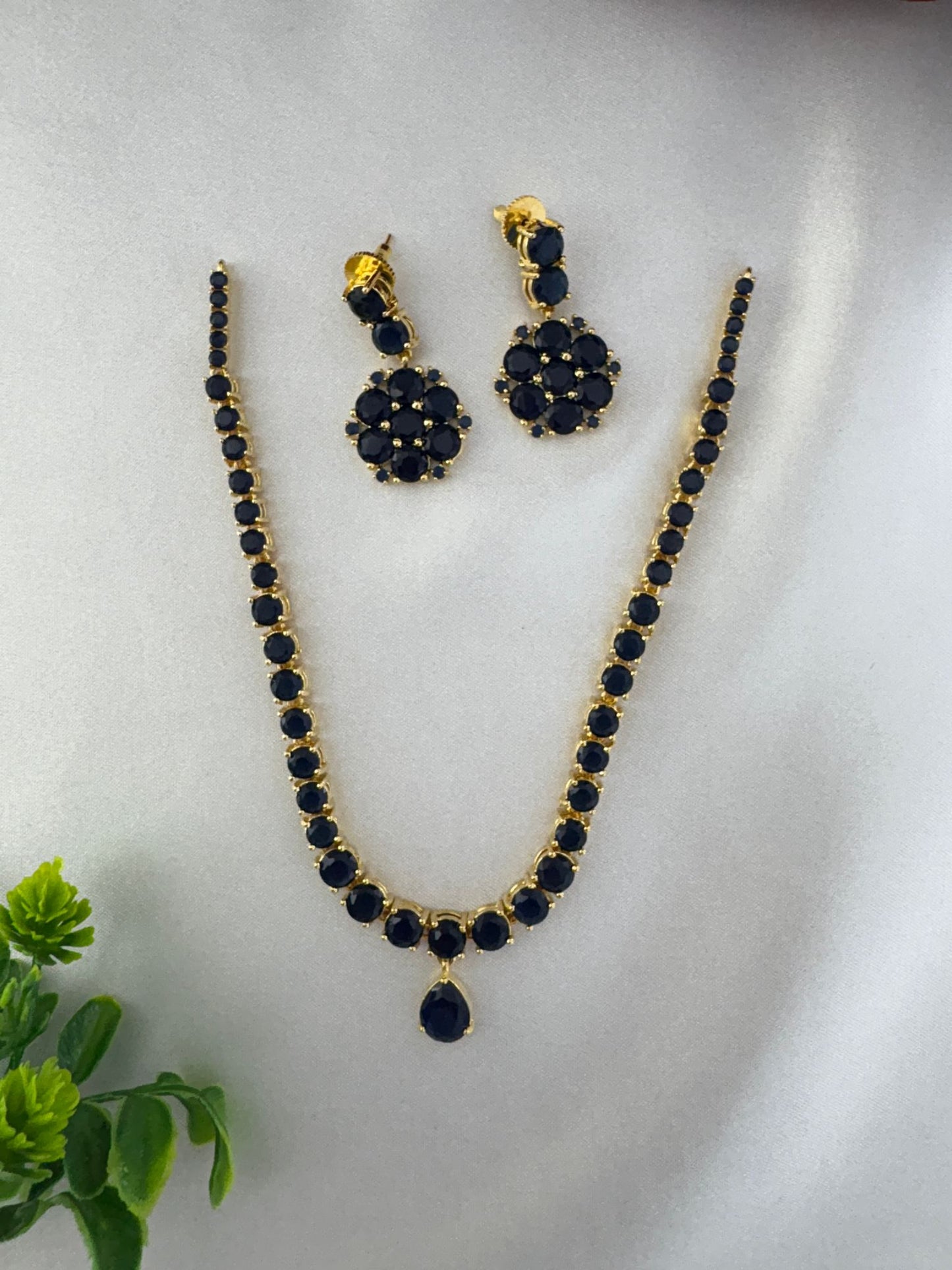 FeelOri Sapphire Hue Blue AD Halo Short Necklace Set - Styled view with necklace and earrings on white satin.