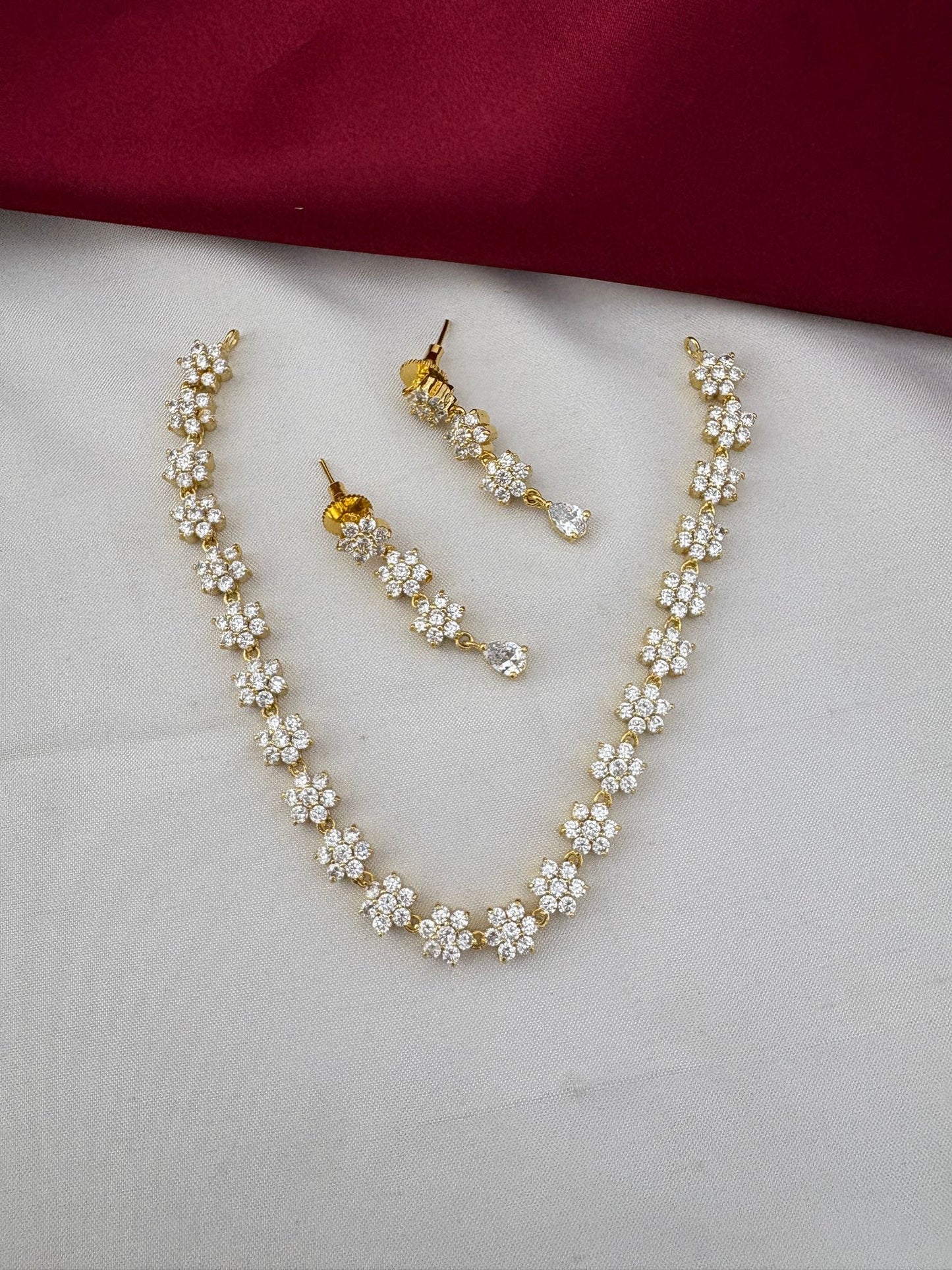 FeelOri Classic Elegance AD Stone Short Necklace Set with solitaire sparkle on dual-tone cream and maroon fabric.