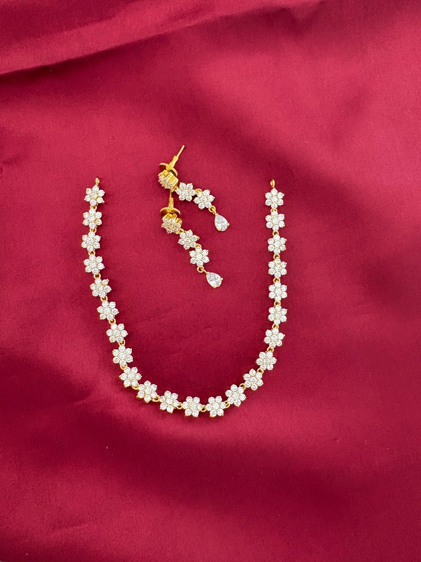 FeelOri Solitaire Sparkle AD Stone Short Necklace Set with matching earrings, floral design, on maroon background.