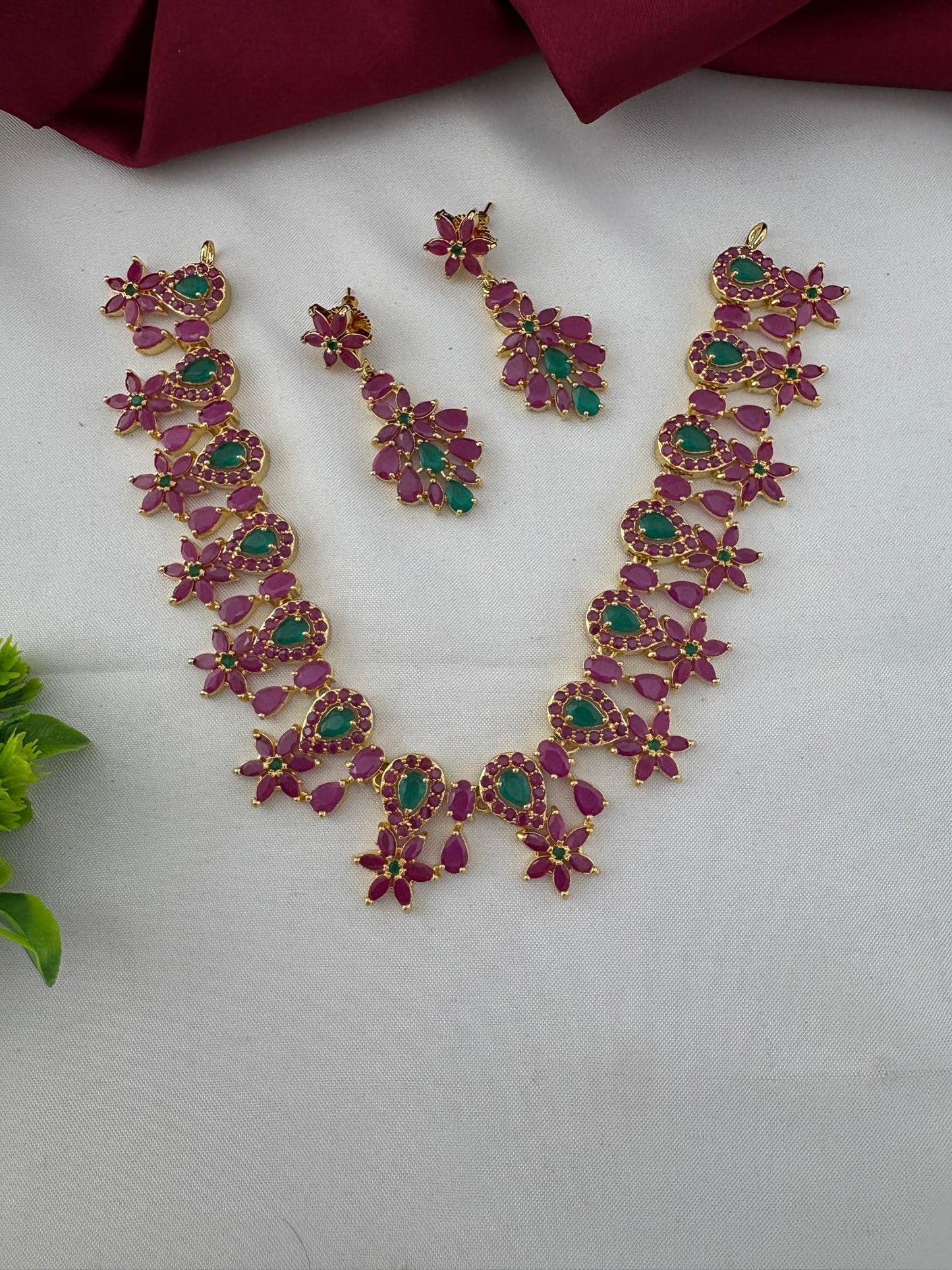 FeelOri Telangana Rani Ruby & Emerald Short Haar-Style Set - Necklace laid flat with earrings, displayed on white background with maroon and green accents.