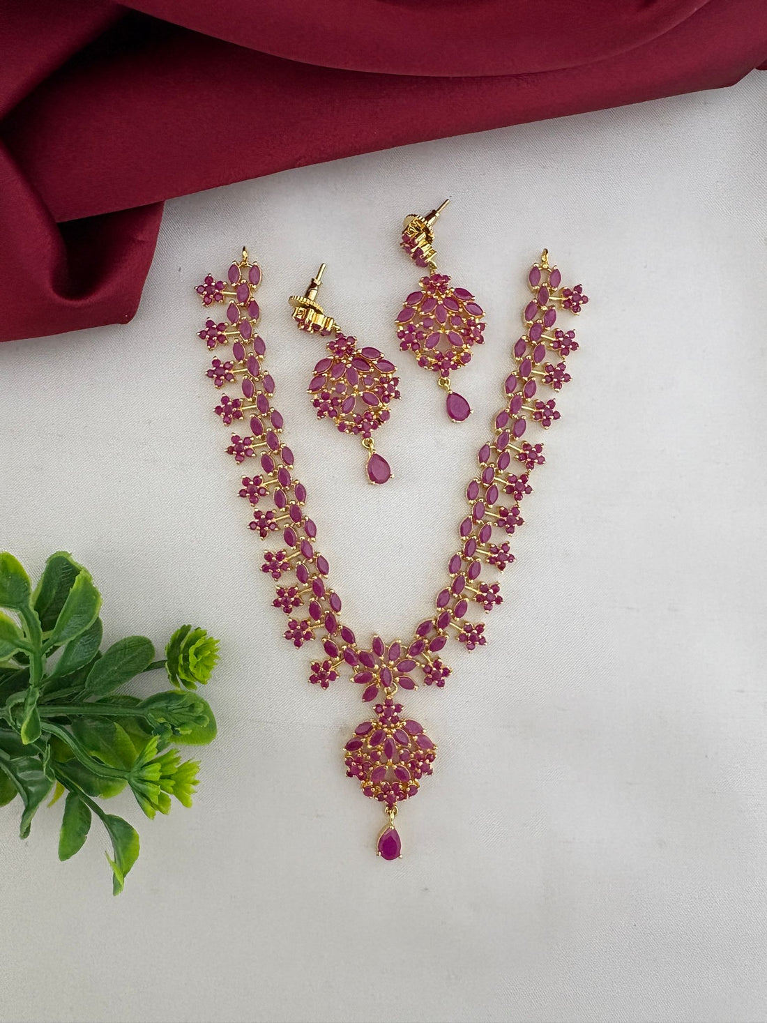 Styled presentation of the FeelOri Temple Design Ruby-Tone CZ Short Necklace Set with earrings, an authentic craft piece by feelori.
