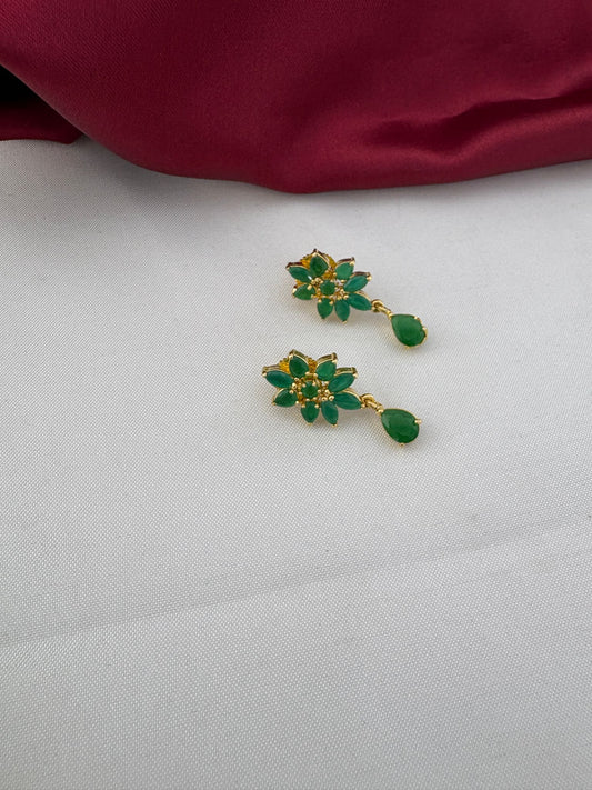Detailed close-up of the FeelOri Urban Oasis Minimalist Emerald Earrings, highlighting the floral design with green stones and gold-tone setting.