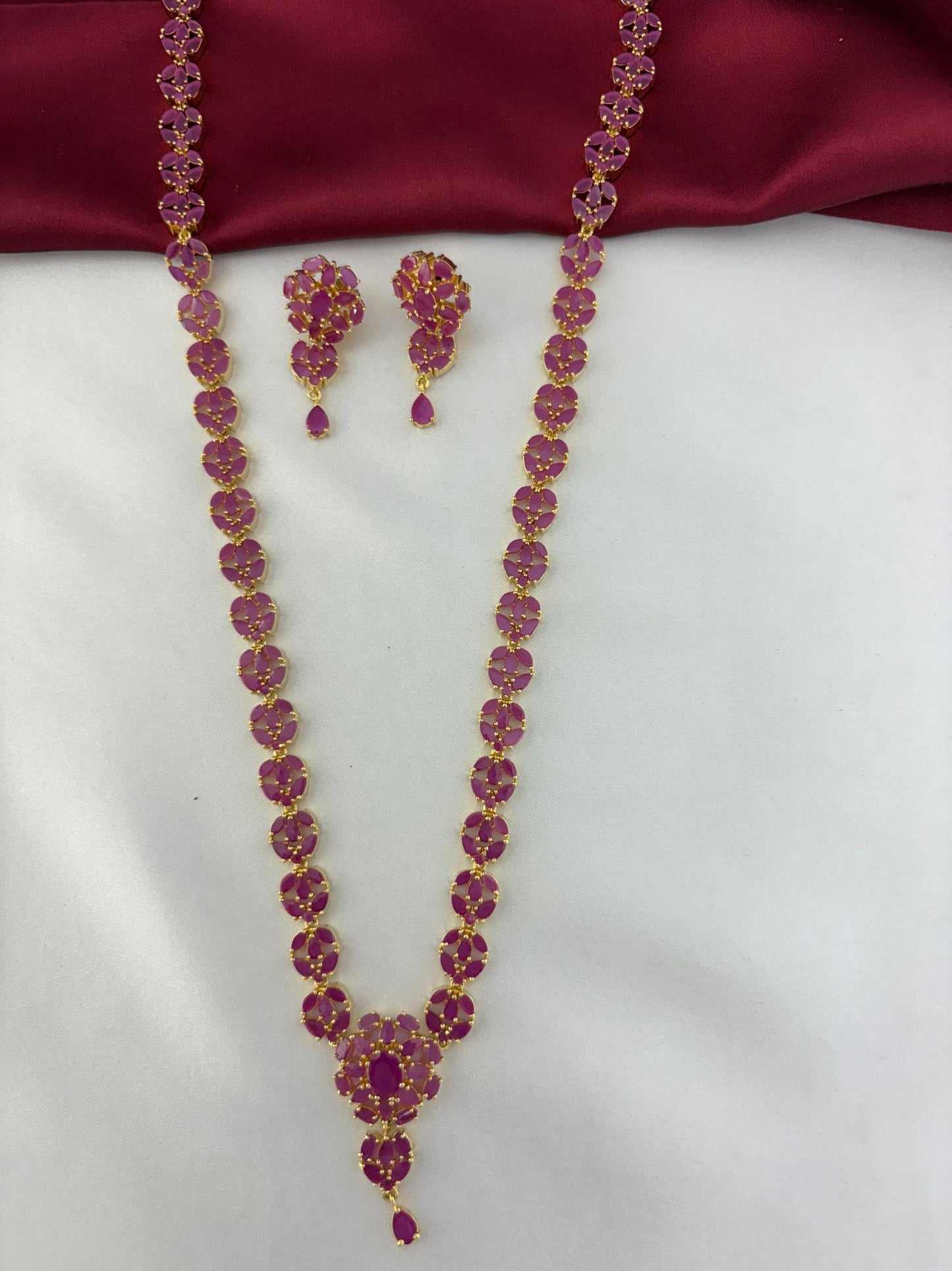 Overhead shot of the FeelOri Vintage Vine Ruby Long Necklace & Earring Set against a contrasting background.