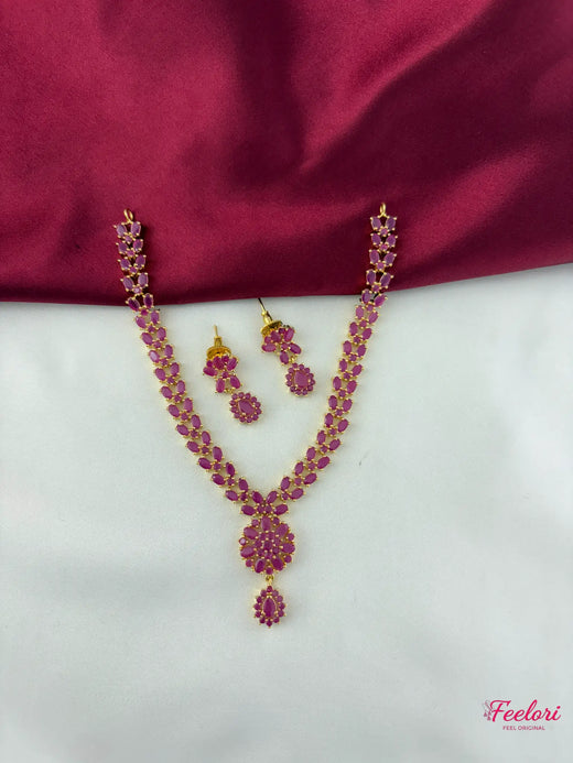 FeelOri Gold Plated Ruby Drop Necklace & Earring Set - Full view showcasing the intricate design and Ruby-Tone CZ-hued stones on a white and maroon background.