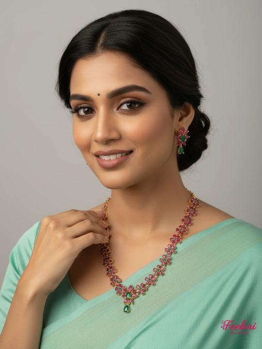 FeelOri Gold Ruby Emerald Floral Necklace Set - Model wearing delicate jewelry with light blue saree.