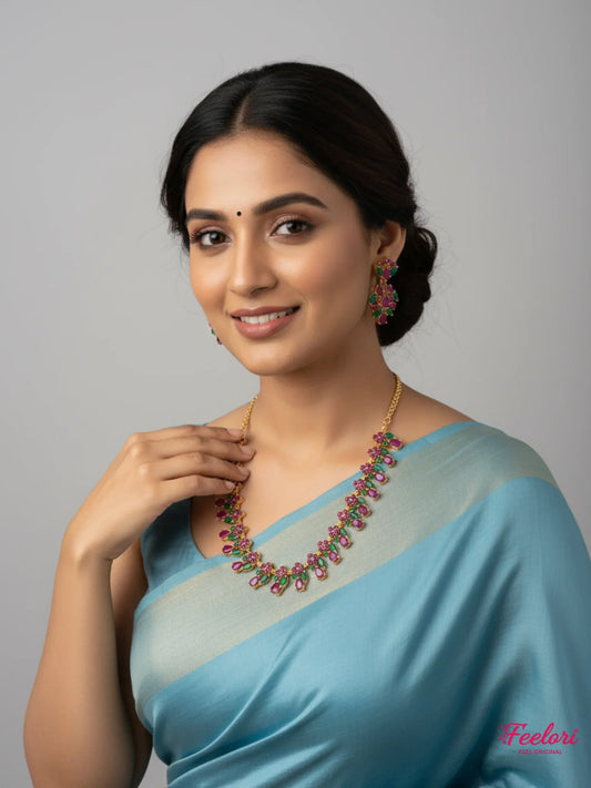 FeelOri Gold Plated Ruby Emerald Petal Necklace Set - Model in light blue saree smiling at camera.