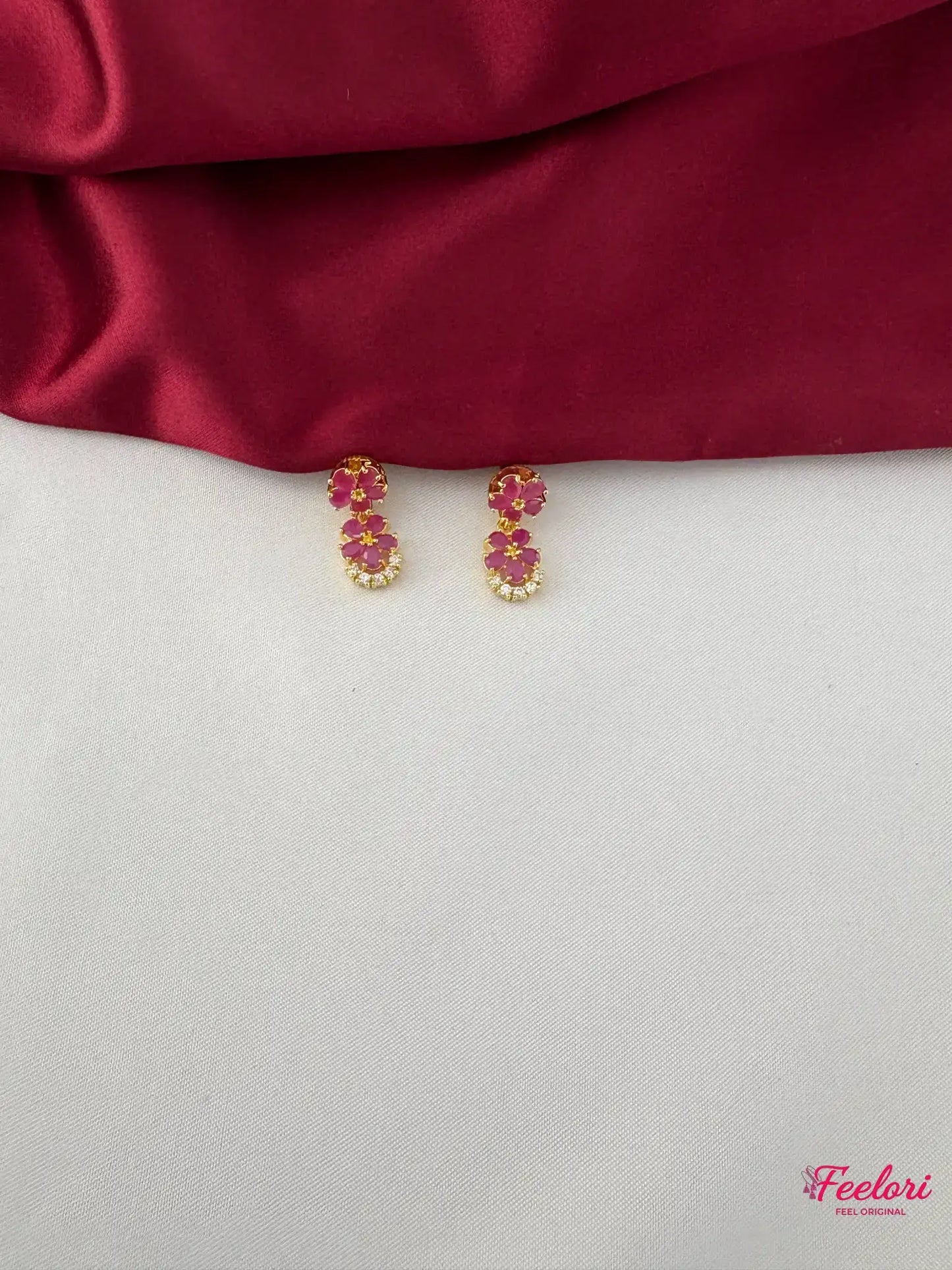 FeelOri Gold Plated Ruby Floral Motif Earrings - Close-up view of the matching earrings, highlighting the two-petal ruby arrangement and clear stone accents.
