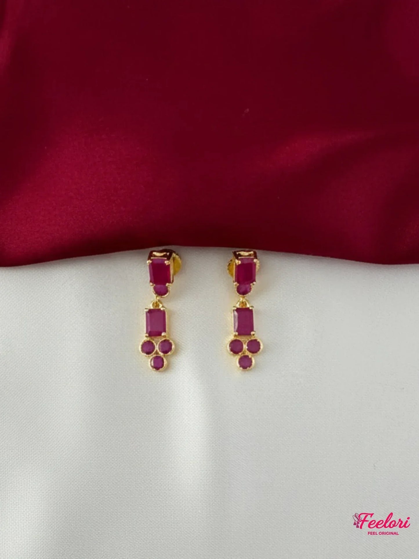 FeelOri Gold Plated Ruby Geometric Earrings - Close-up view of the matching drop earrings featuring rectangular and clustered round ruby-hued stones.