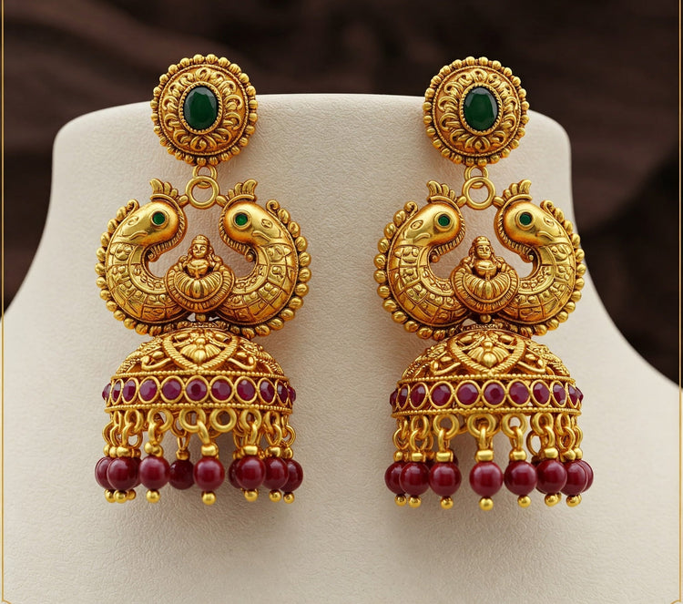 Pair of traditional Feelori Makarakundanalu earrings in gold plate with ruby and emerald stones, showcasing the unique Makara design - South Indian heritage jewelry.