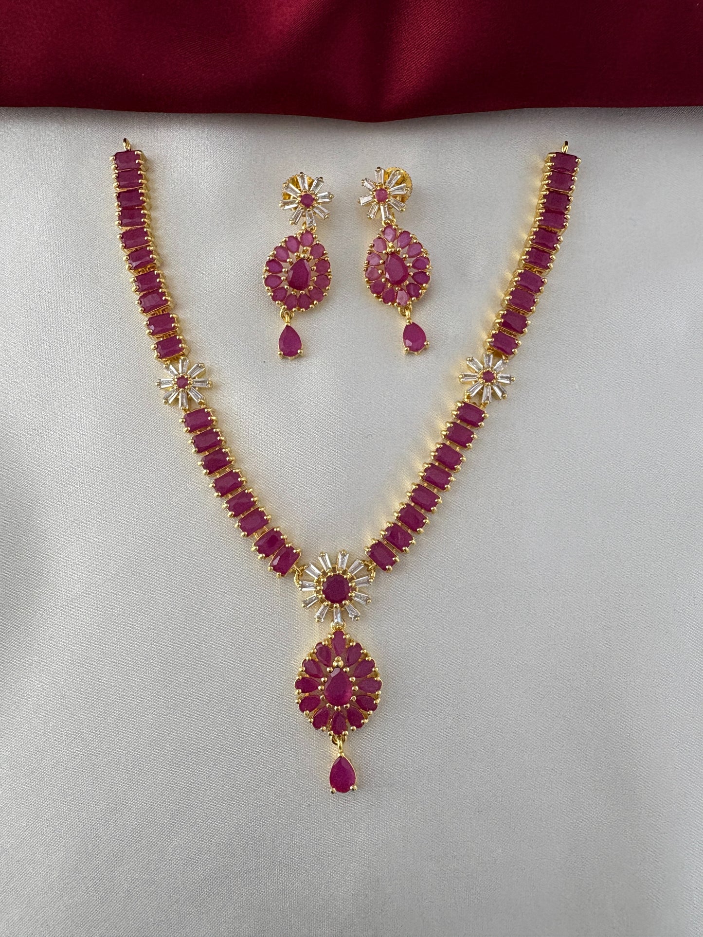 FeelOri Gold Plated Ruby Floral Cluster Necklace Set - Front view showcasing intricate necklace design with matching earrings on a white and maroon backdrop.