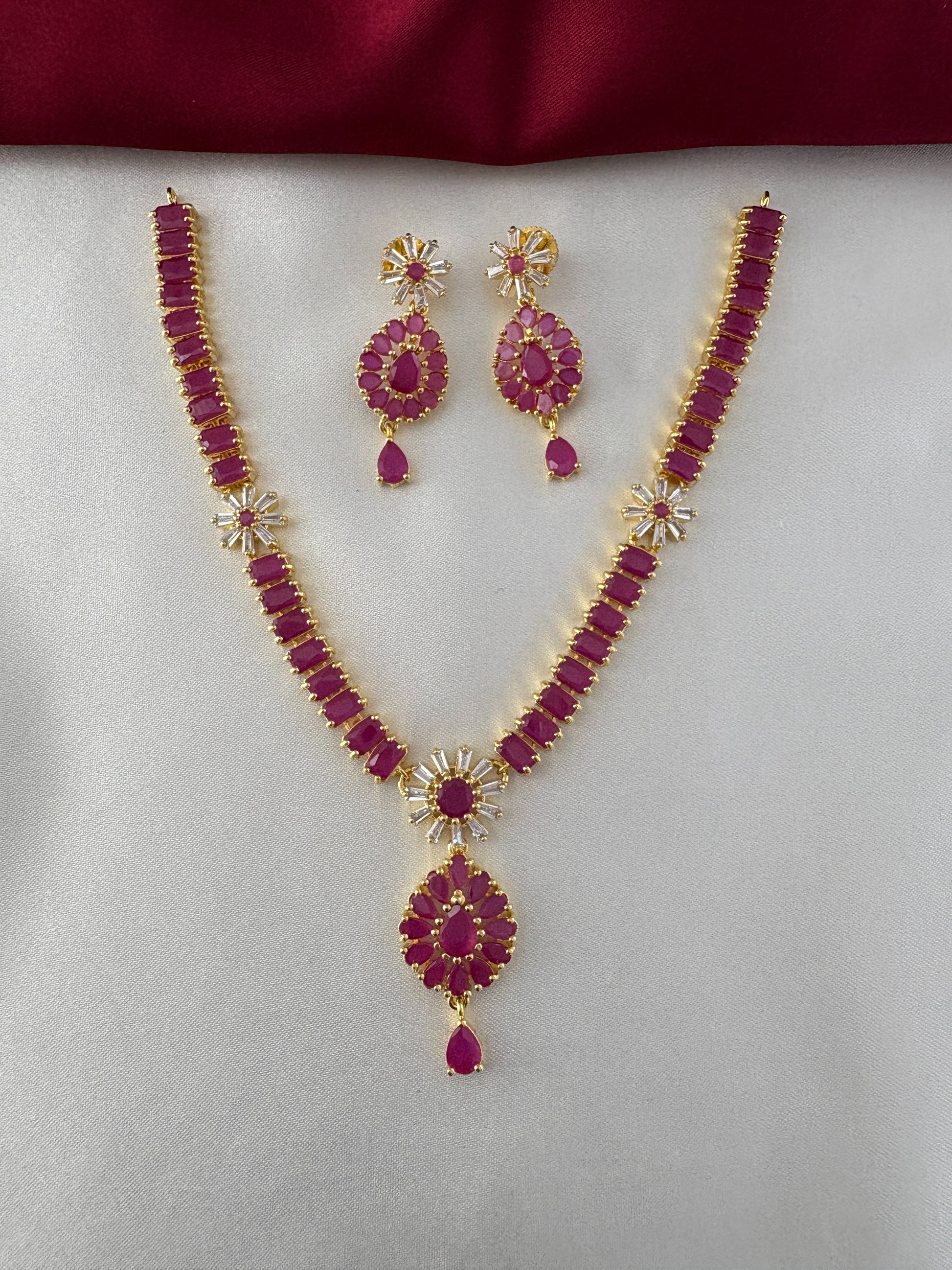 FeelOri Gold Plated Ruby Floral Cluster Necklace Set - Front view showcasing intricate necklace design with matching earrings on a white and maroon backdrop.