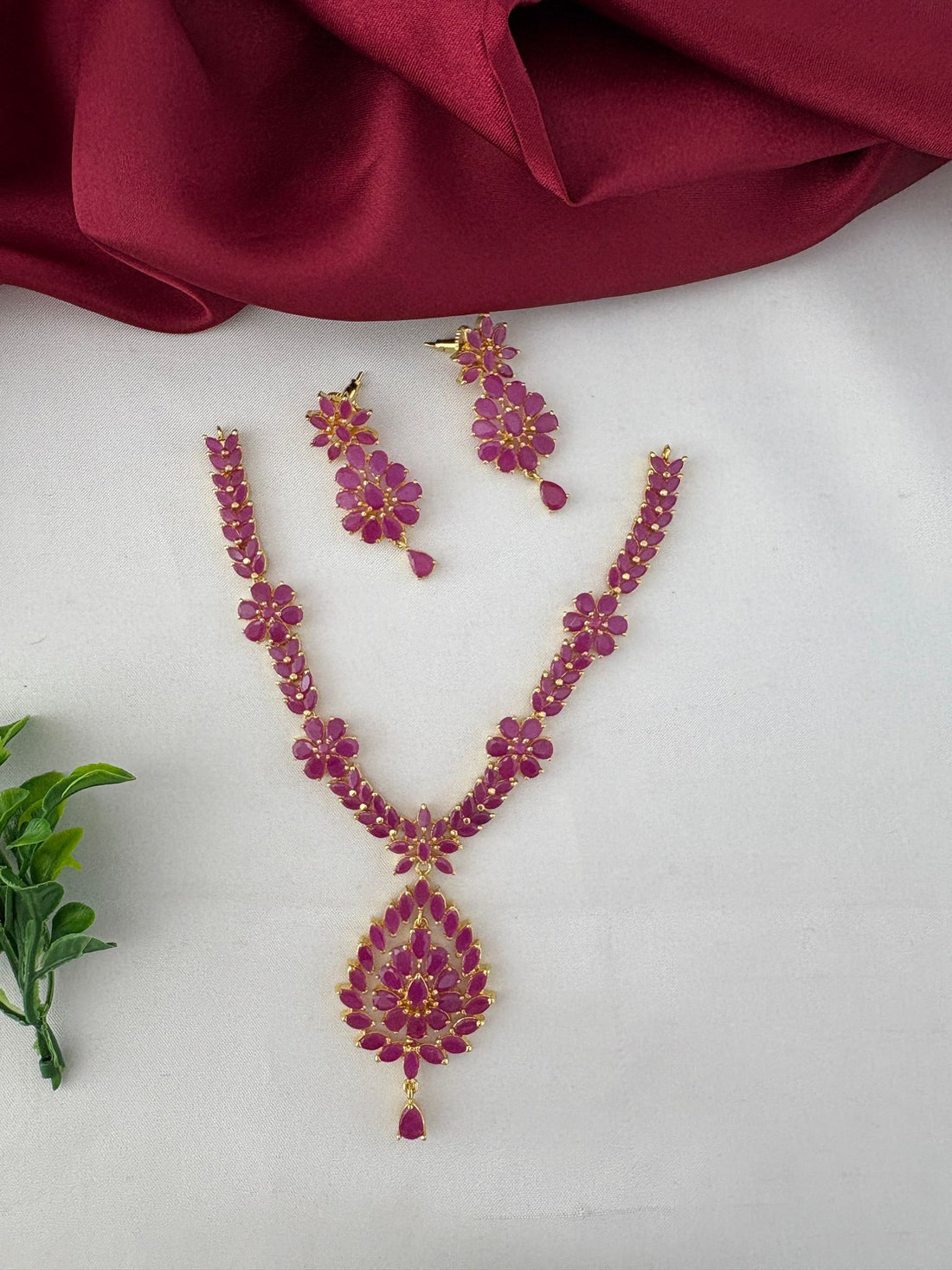 Top-down view of the FeelOri Traditional Ruby-Tone CZ Short Necklace Set, emphasizing the ruby stones and ethnic pattern.