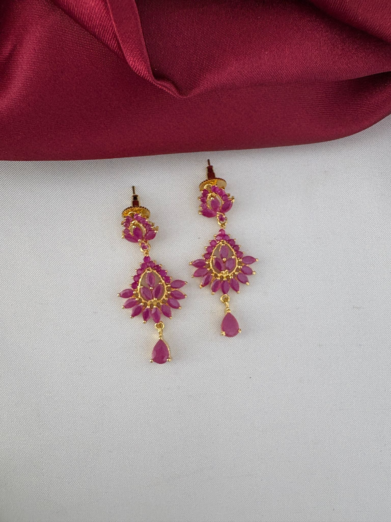 Close-up of FeelOri Exquisite Ruby-Tone CZ Earrings, part of the bridal short necklace set, showcasing detailed craftsmanship and rich ruby color.