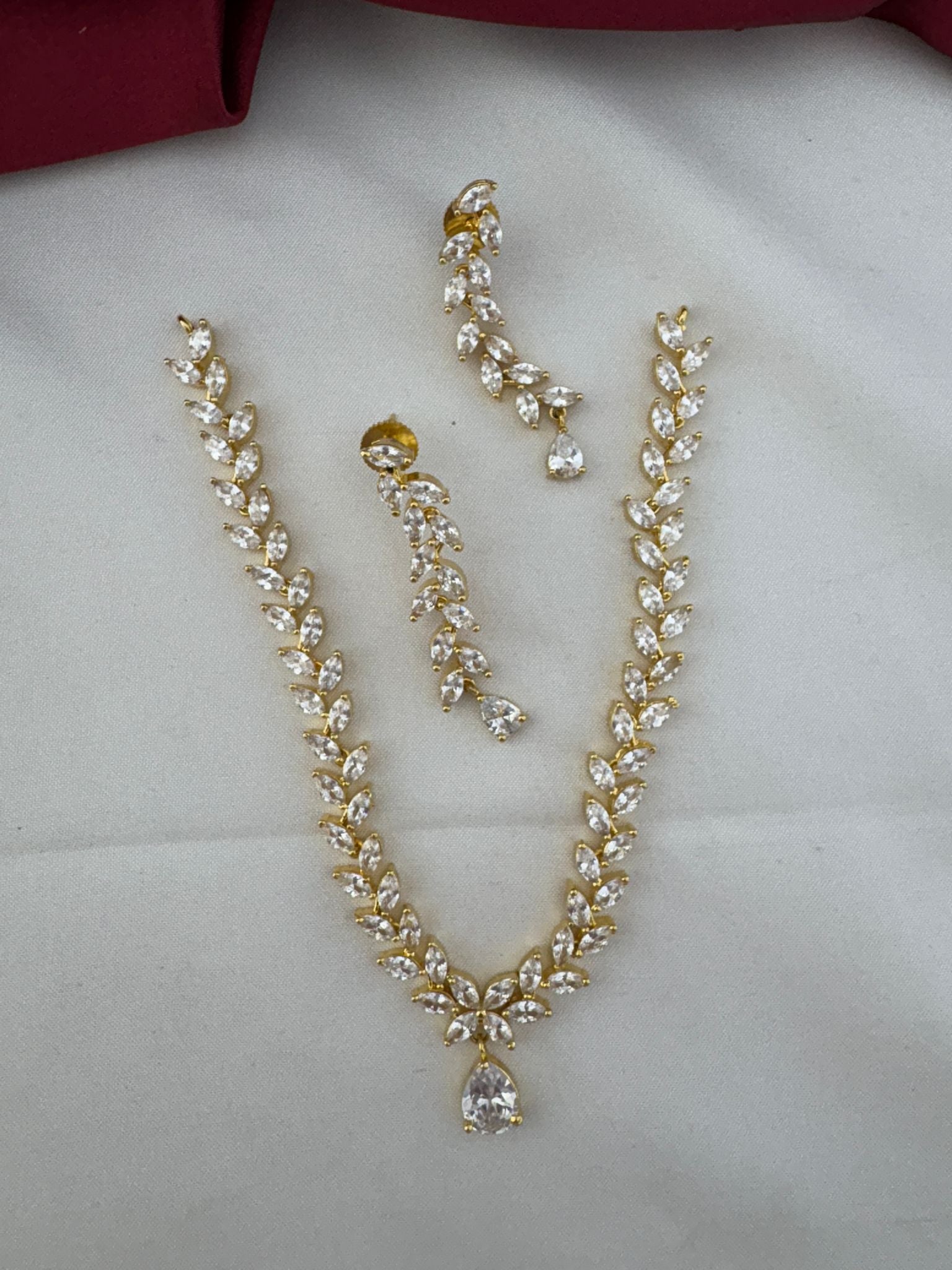 FeelOri Festive Dazzle AD Stone Floral Short Necklace Set with matching earrings, top view on a white fabric background.