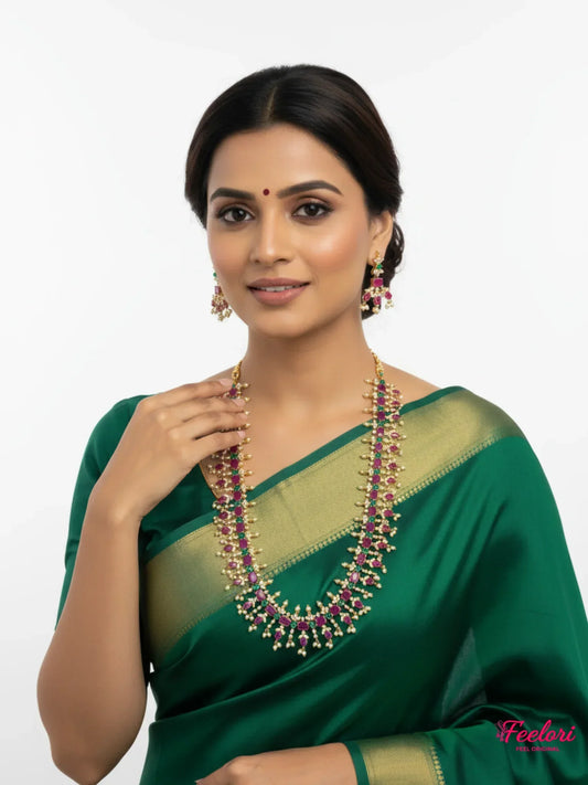 FeelOri Gold Plated Ruby Emerald Pearl Haaram Necklace Set - Model wearing traditional deep green saree.