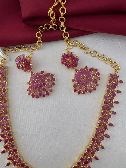 Close-up detail of the Feelori Gorgeous Original Ruby Short Necklace and Earrings set, showcasing the intricate ruby stone work and gold plating.