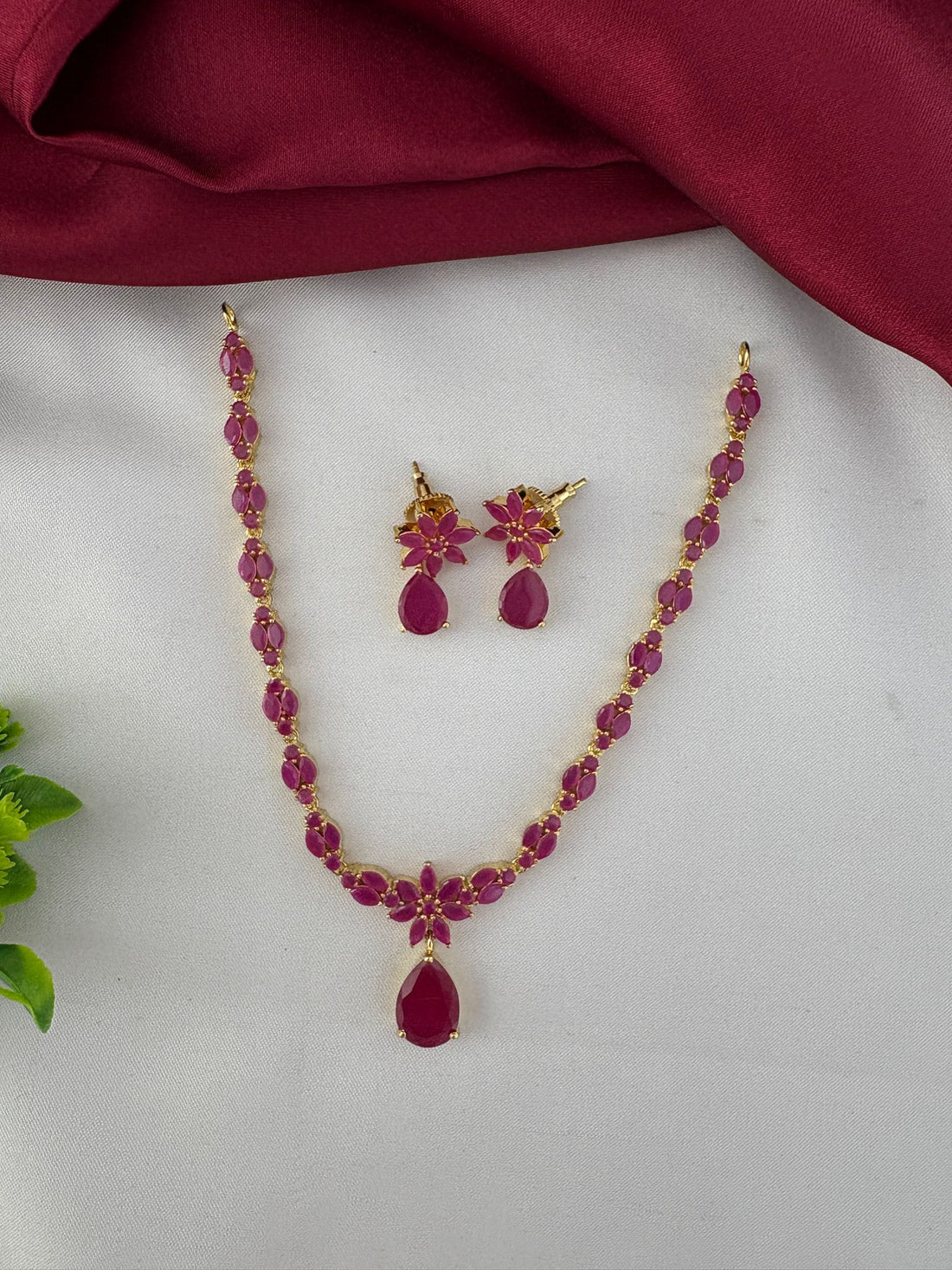 FeelOri Heritage Ruby-Tone CZ Short Necklace Set - Full view of necklace and earrings on a white and maroon background.