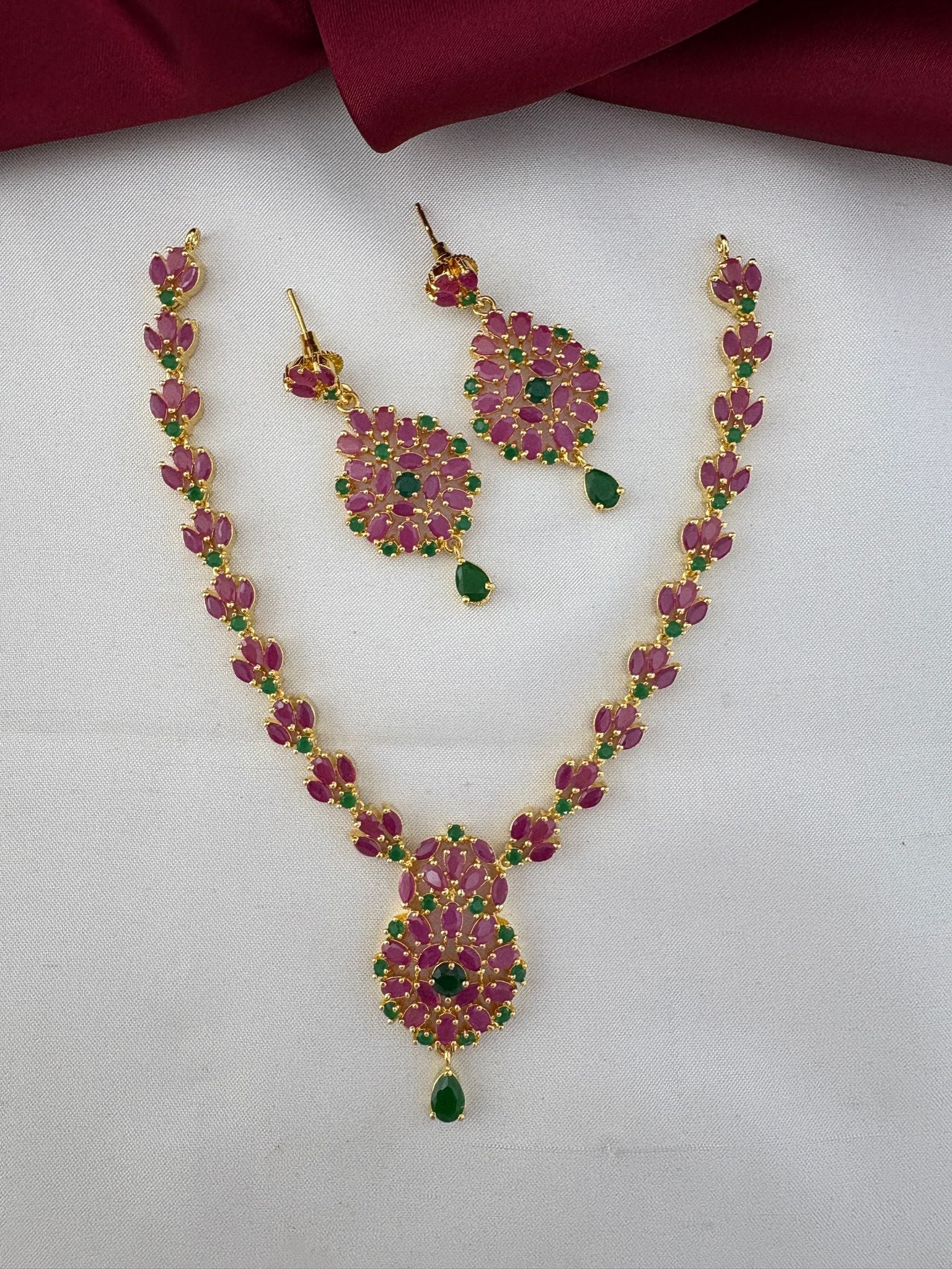 FeelOri Kerala Temple Duo Ruby & Emerald Necklace Set - Styled on fabric.
