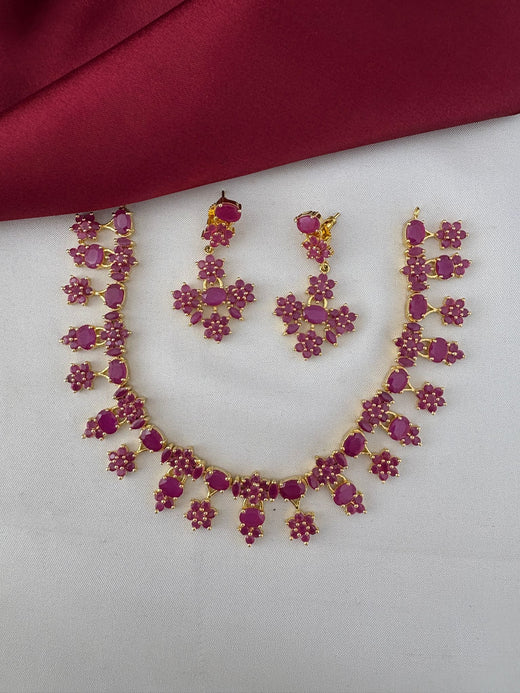 FeelOri Nakshi Work Ruby-Tone CZ Short Necklace and Earrings Set - Telangana Art. Full view of the ruby jewelry set on a white and maroon background.