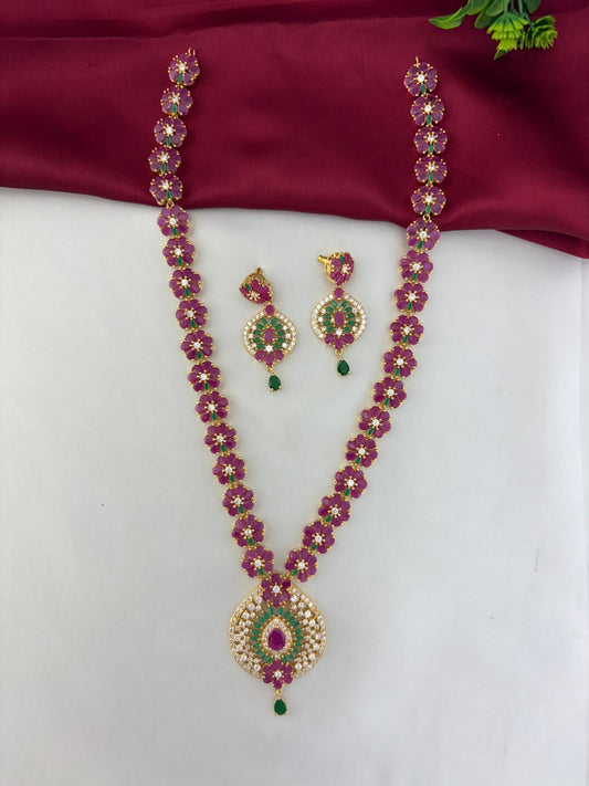 Feelori traditional gold-plated ruby, emerald, and AD stone necklace and earring set, front view on a white and maroon background.