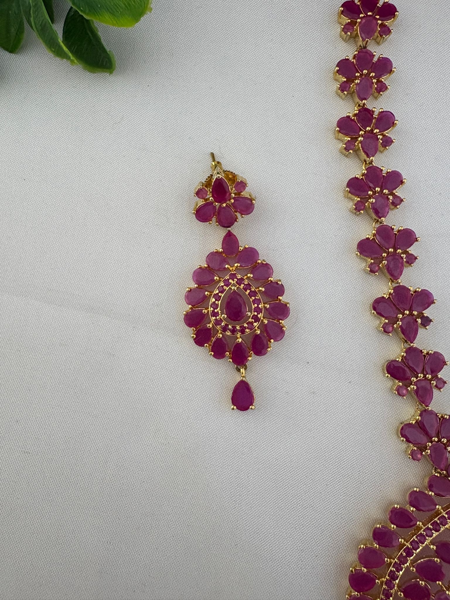 Close-up shot of an earring and necklace detail from the FeelOri Minimalist Ruby-Tone CZ Short Necklace Set, highlighting the stone cuts and craftsmanship.