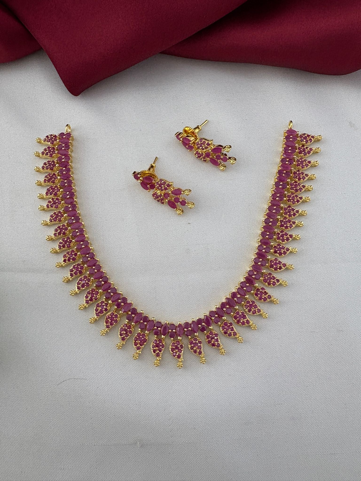 FeelOri Bridal Wear Ruby-Tone CZ Short Necklace Set - South India Special - Full view of necklace and earrings on a white and maroon background.