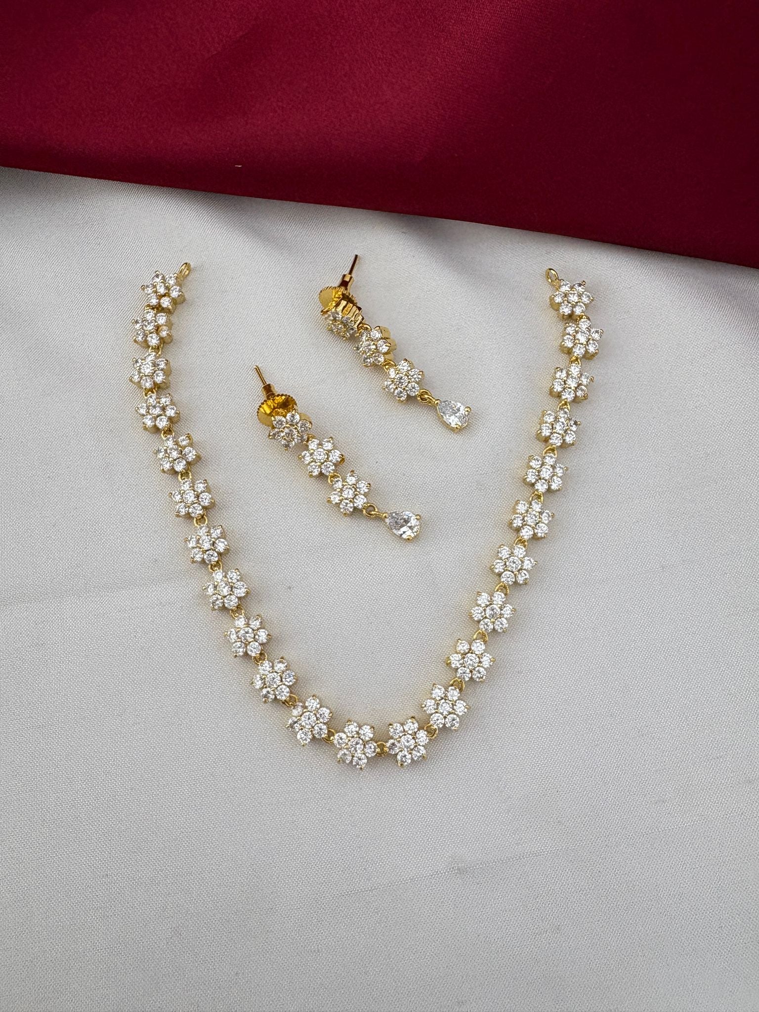 FeelOri Classic Elegance AD Stone Short Necklace Set with solitaire sparkle on dual-tone cream and maroon fabric.