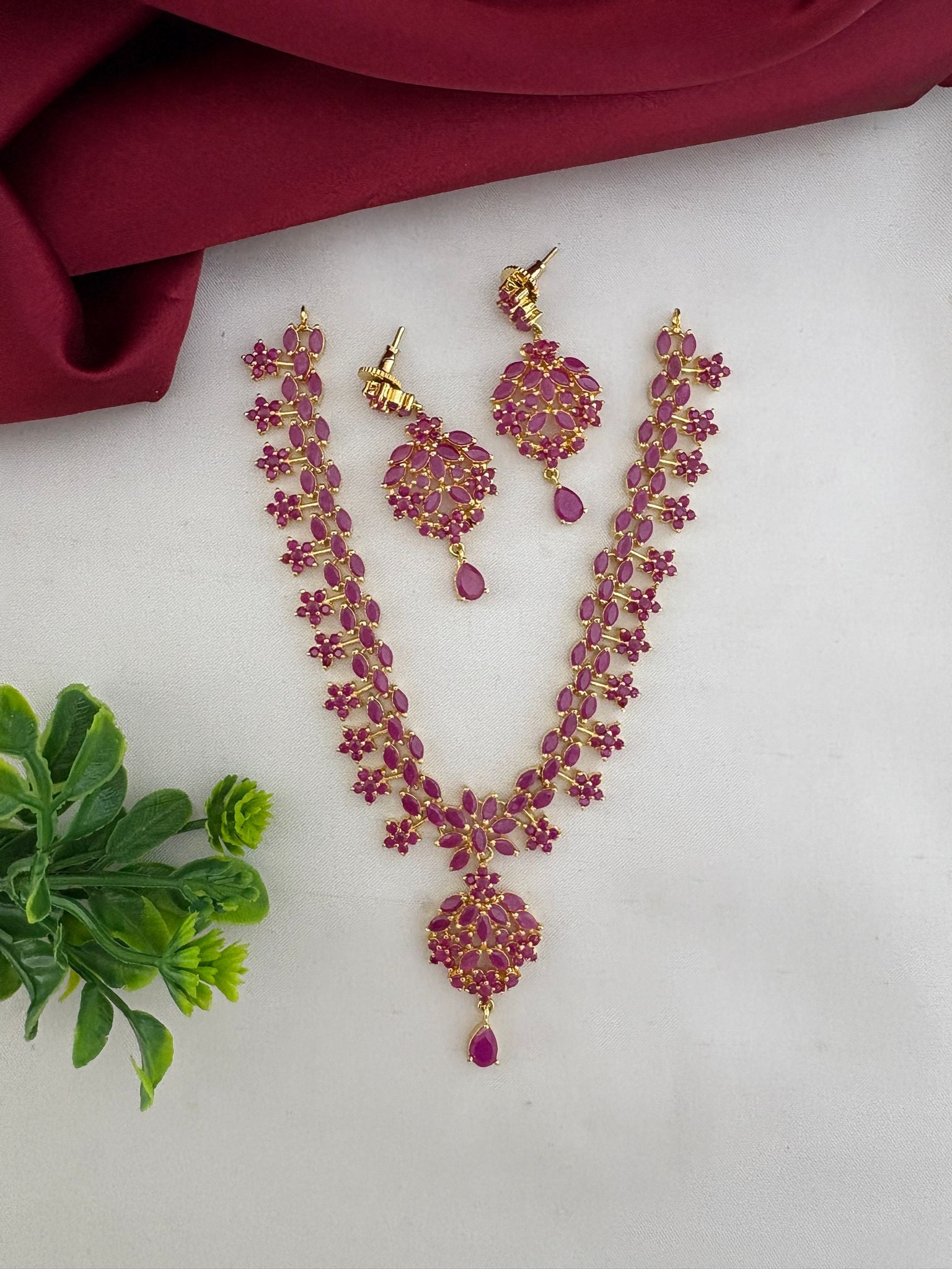 Styled presentation of the FeelOri Temple Design Ruby-Tone CZ Short Necklace Set with earrings, an authentic craft piece by feelori.