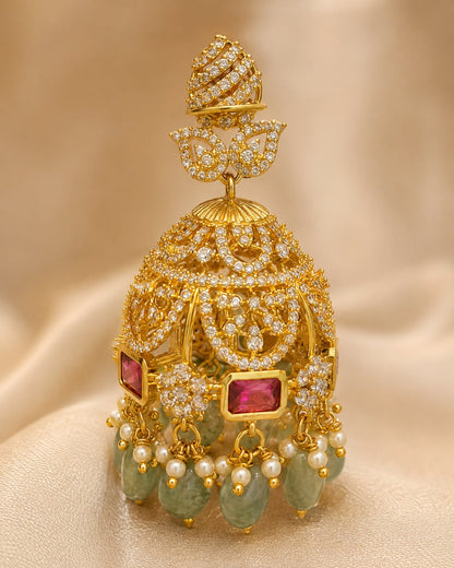 Close-up of gold-plated emerald-drop CZ leaf jhumka earrings showing leaf motifs, clear CZ settings, emerald-green drops and gold bead fringe