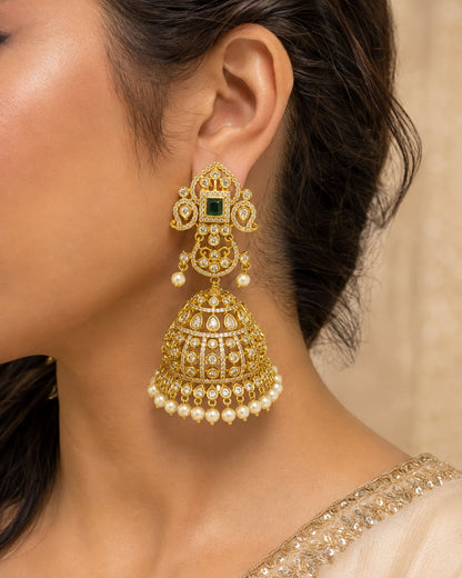 Model wearing FeelOri grand gold-plated emerald CZ jhumka earrings with pearl-look fringe for Indian occasion styling