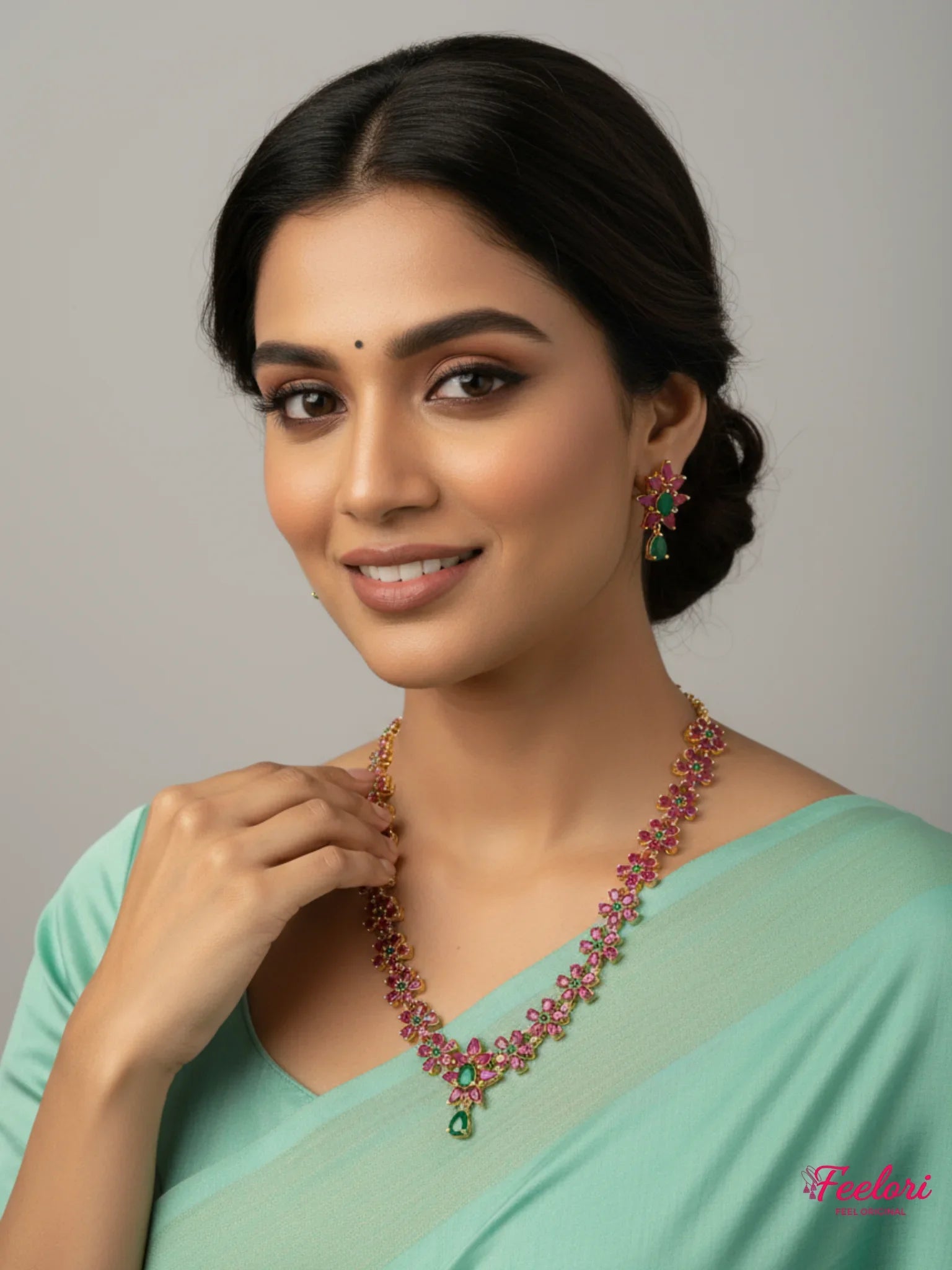 FeelOri Gold Ruby Emerald Floral Necklace Set - Model wearing delicate jewelry with light blue saree.