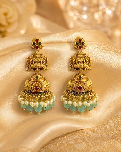 FeelOri gold-plated ruby and emerald jhumka earrings styled with saree fabric for Indian occasion wear