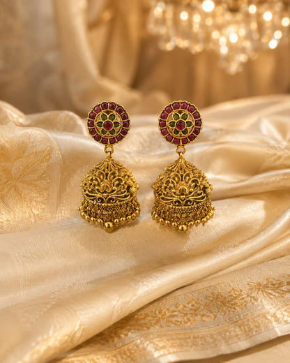 FeelOri gold-plated ruby and emerald jhumka earrings styled with saree fabric for Indian occasion wear