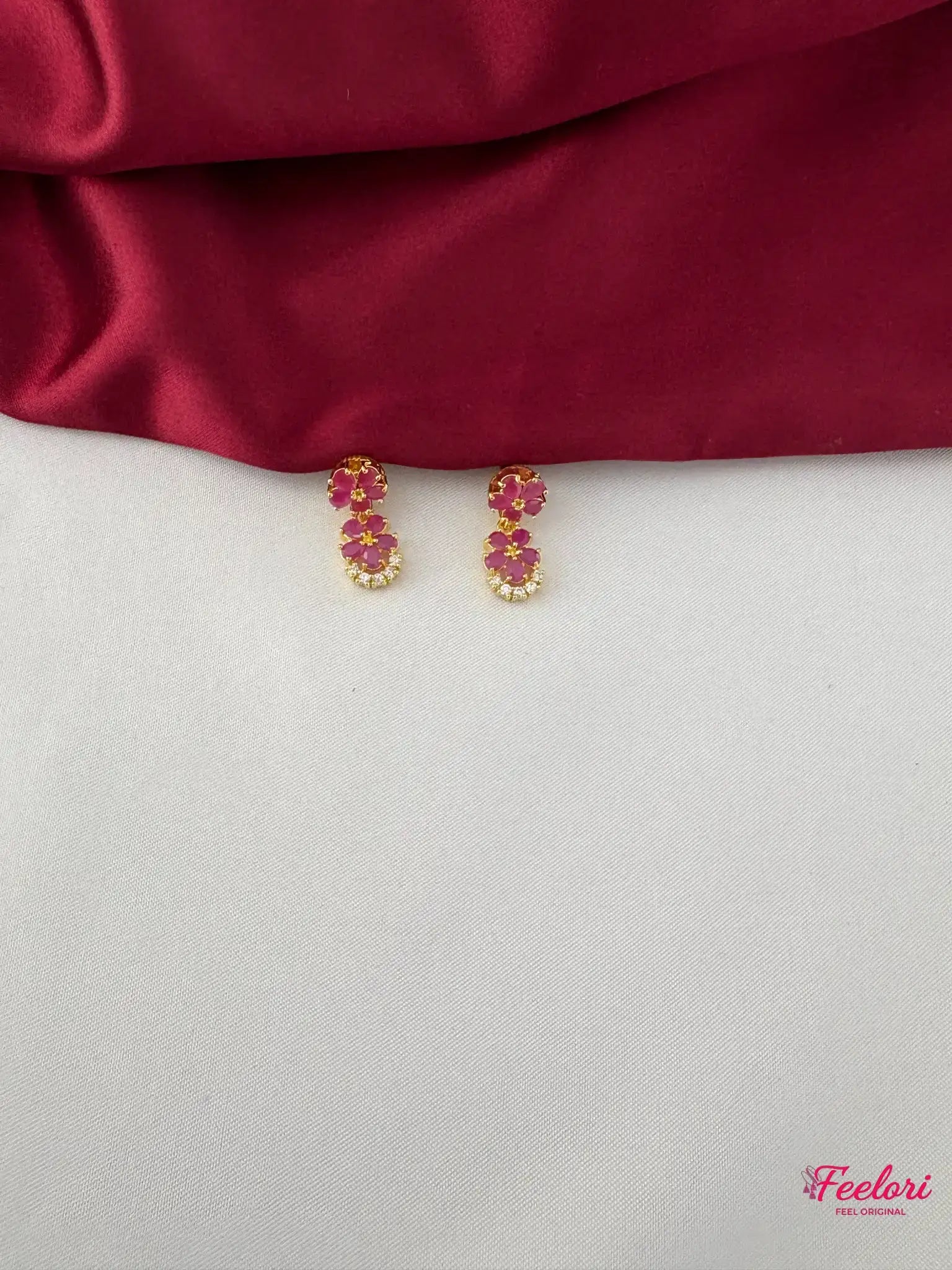 FeelOri Gold Plated Ruby Floral Motif Earrings - Close-up view of the matching earrings, highlighting the two-petal ruby arrangement and clear stone accents.
