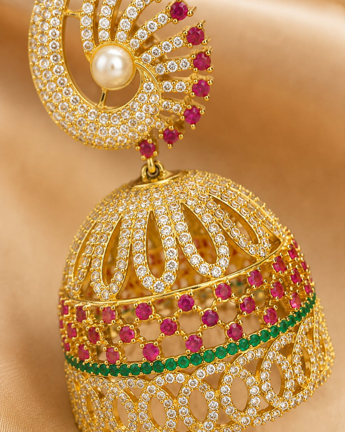 Close-up of gold-plated ruby fan CZ jhumka earrings with pearl-look drops showing ruby-red fan top, open petal CZ bell and pearl-look drops