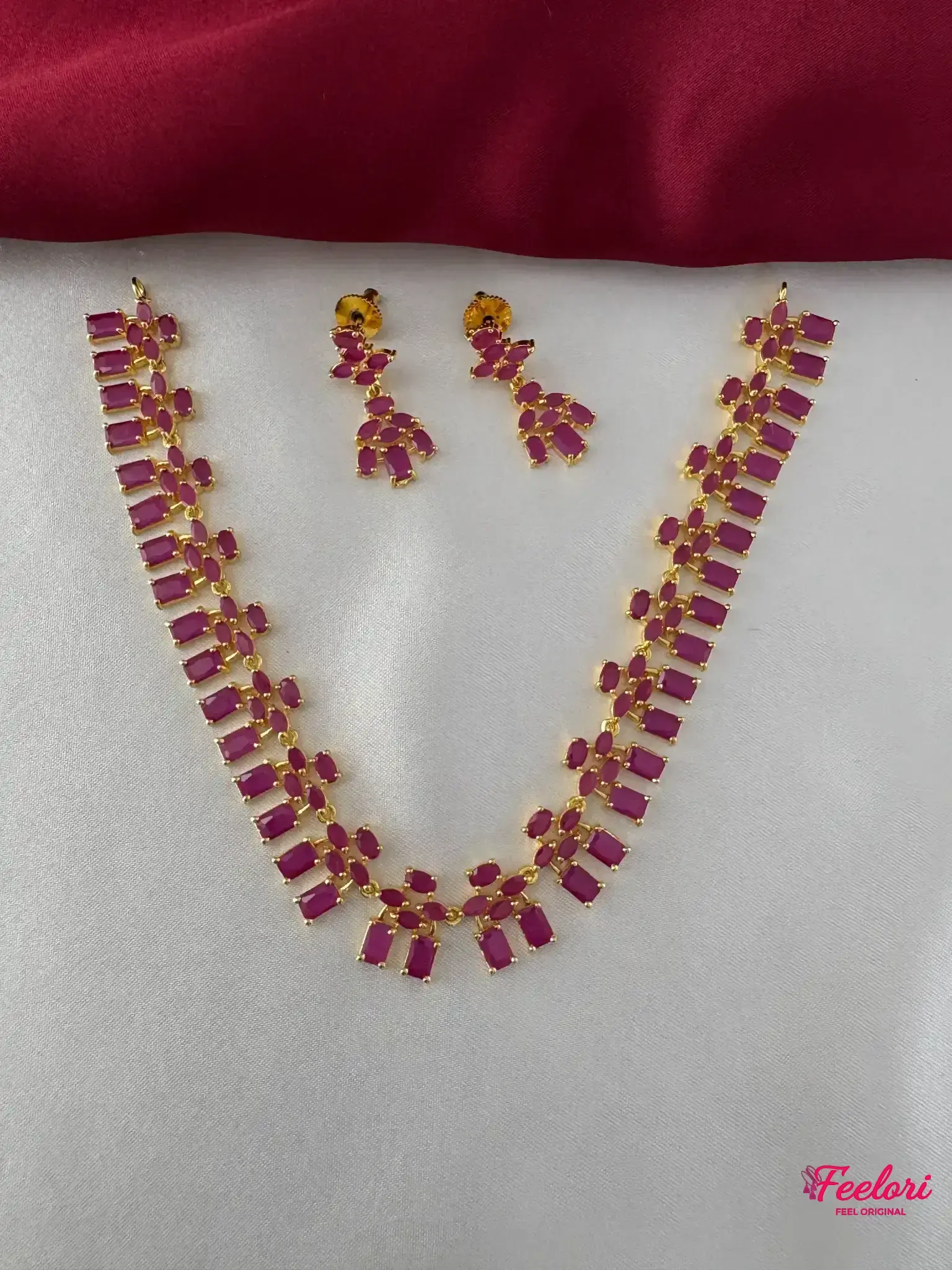 FeelOri Gold Plated Ruby Cluster Necklace Set - Full view showcasing the matching necklace and drop earrings on a white and maroon background.