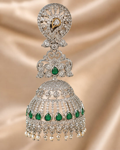Close-up of silver-tone rhodium-finish emerald-fringe CZ jhumka earrings showing clear CZ settings, emerald-green drops and pearl-look fringe